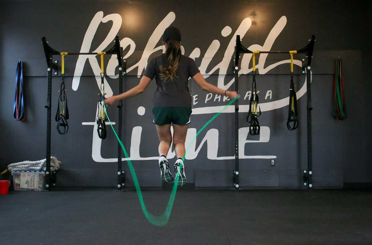 Femme faisant de la corde à sauter verte dans une salle de sport